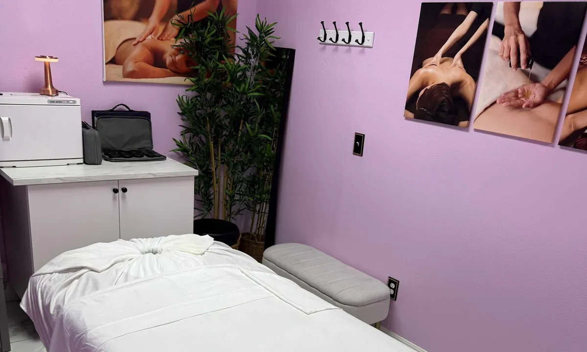 Massage table beneath spa artwork with a towel warmer ready on the counter