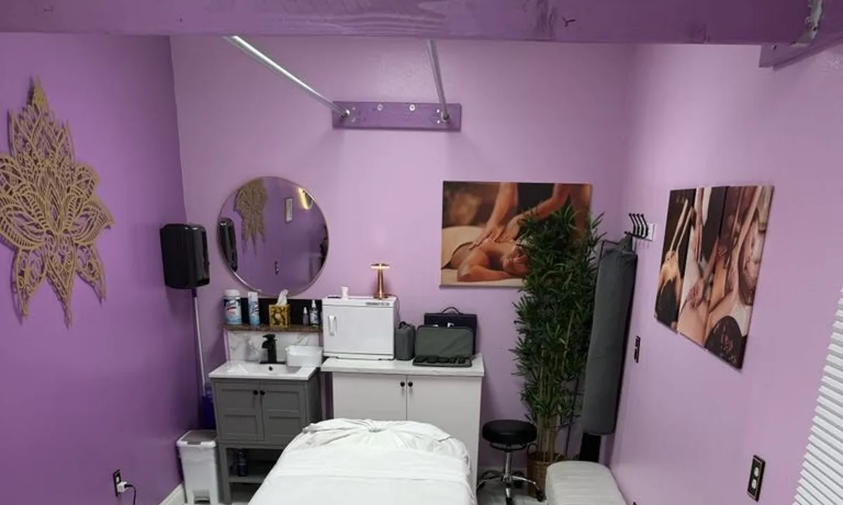 Treatment room with round mirror, sink, and warmly lit wall art