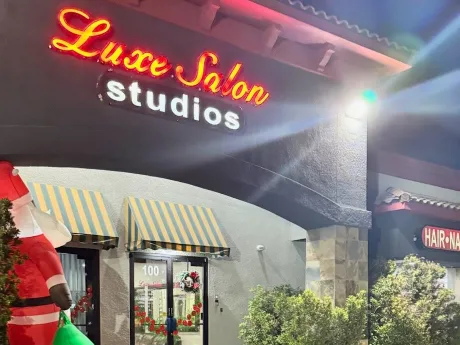 Luxe Salon Studios entrance at night with its neon sign — Massage Devine is inside